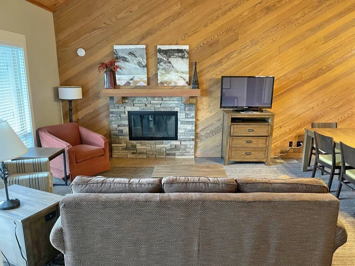 A cozy living area with a fireplace as the focal point, complemented by a comfortable sofa, television, and tasteful artwork. The space feels inviting and warm—ideal for relaxing evenings, socializing, or unwinding after a day of resort activities.