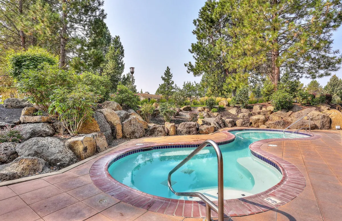 An inviting swimming pool bordered by natural rock formations and lush greenery, suggesting a relaxing summer environment ideal for cooling off after outdoor activities. The tranquil setting hints at the variety of warm-weather adventures available nearby.