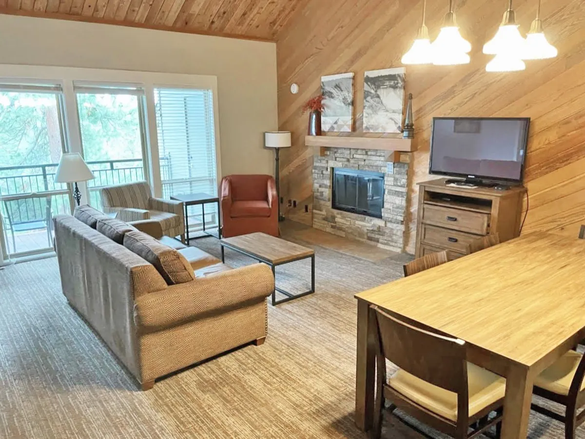 This image captures a cozy, open-concept living and dining space featuring a welcoming fireplace, comfortable sofa, and a dining table. The warm lighting and inviting arrangement evoke feelings of comfort and togetherness, with the fireplace as a natural focal point, ideal for relaxing or gathering with loved ones.