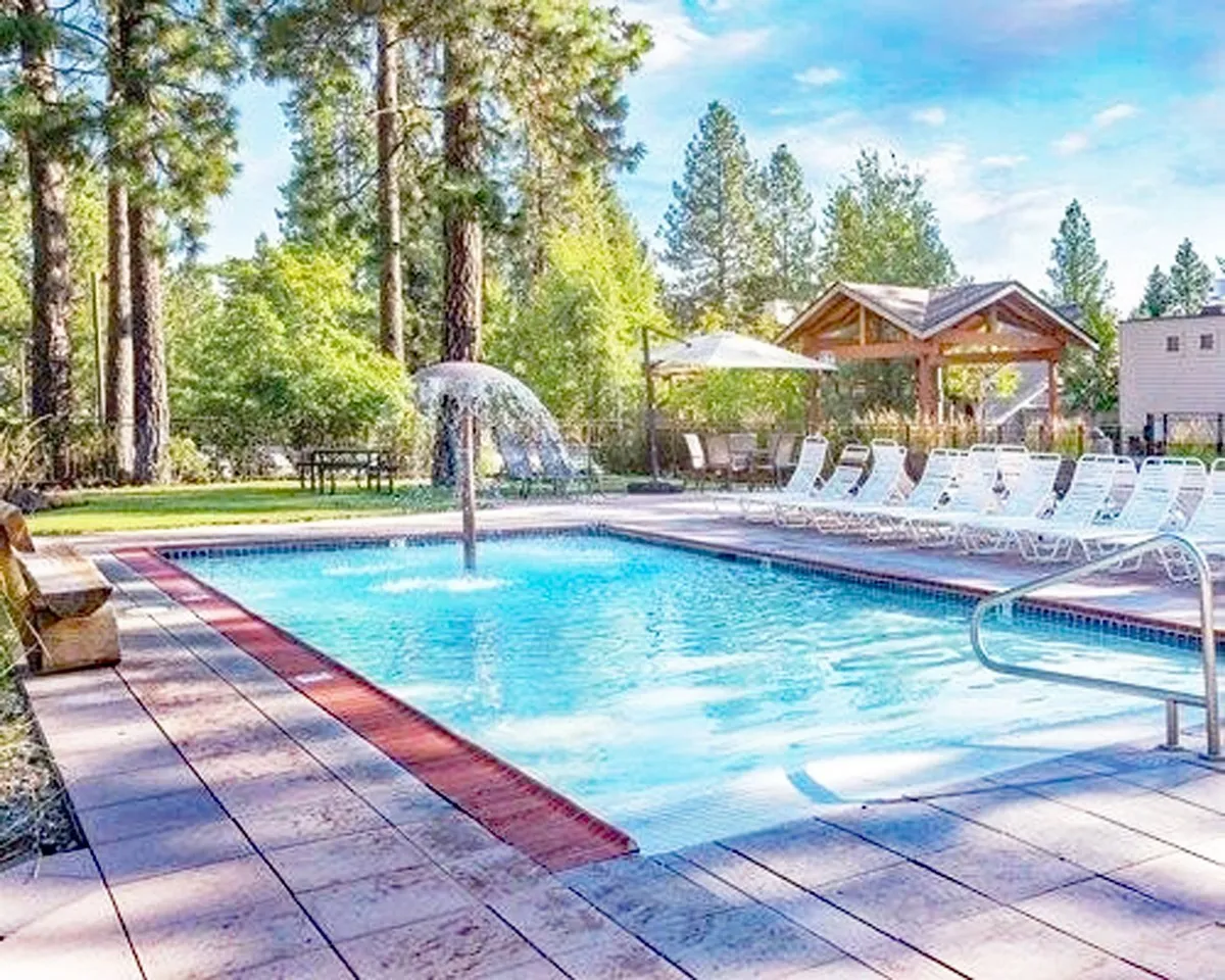 The scene features a tranquil swimming pool with a fountain, sun loungers, and a gazebo, all set amidst lush greenery. The serene, leisure-focused environment captures the resort's laid-back feel and natural surroundings, supporting the narrative of relaxation and pet-friendly outdoor enjoyment.