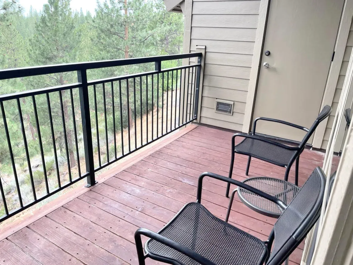 A tranquil balcony scene with chairs and a view of surrounding pine trees. The outdoor seating invites guests to step outside with a morning coffee or evening toast, enjoying the fresh air and serene resort setting.